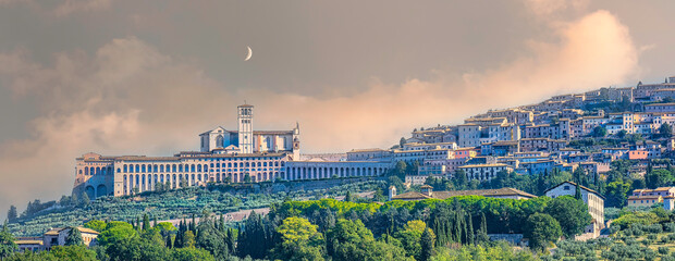 Panoramic view of Assisi with the moon above and the fog coming in