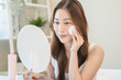 Young asian woman applying moisturizer on face after use toner cleansing remove cosmetic.