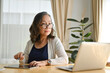 © bongkarn - Successful Asian aged-woman examining a business online report on laptop computer.