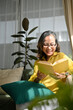 © bongkarn - Beautiful Asian aged woman enjoy reading a book in her comfortable living room.