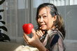 © bongkarn - Attractive asian middle-aged woman holding a red heart shape with a beautiful smile.