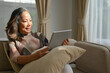 © bongkarn - Attractive asian retired woman relaxes in the living room and using portable tablet.