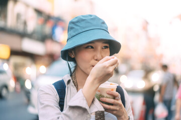 Wall Mural - Closeup young adult asian foodie woman backpack traveller eating asia dessert street food