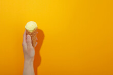 Female Hand With Ice Cream On Orange Background, Space For Text