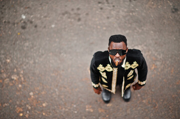 Wall Mural - Mega stylish african man in traditional jacket pose. Fashionable black guy in sunglasses with cigar.