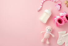 Baby Accessories Concept. Top View Photo Of Pink Booties Socks Knitted Teddy-bear Toy Pacifier Chain Wooden Rattle And Bottle On Isolated Pastel Pink Background With Copyspace
