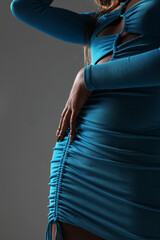 Wall Mural - Cropped shot of female body part in blue dress posing over grey background.