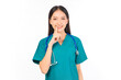 © Png - Video - Photo - Portrait of professional confident young asian female smiling doctor in green scrubs showing presenting finger to stop talking sign gesture silence and secret concept.