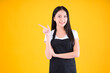 © Png - Video - Photo - pretty asian female smile wearing black apron show and present pointing fingers copy space for your advertisement yellow background.