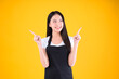 © Png - Video - Photo - pretty asian female smile wearing black apron show and present pointing fingers copy space for your advertisement yellow background.