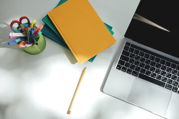 White office table with laptop, notebooks and office supplies in green glass. Flat lay