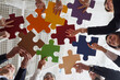 © Studio Romantic - Business solutions. Joyful male and female office workers put together colored pieces of puzzle at meeting in office. Business team easily solves complex problems at work. Bottom view. Close up.