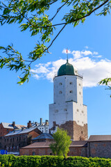 Poster - Medieval fortress in Vyborg. Castle on the water against the blue sky with green foliage
