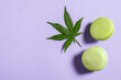 Top view macaroon and cannabis leaf on light violet background, copy space.