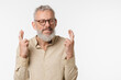 © InsideCreativeHouse - Making a wish. Hope concept. Caucasian mature middle-aged man wearing beige shirt and glasses crossing fingers with eyes closed for good luck, praying to God isolated in white background