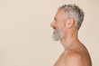 © InsideCreativeHouse - Side view portrait of caucasian mature middle-aged shirtless naked with bare shoulders man with grey hair and beard isolated in beige background. Male beauty concept.