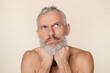 © InsideCreativeHouse - Pensive thoughtful caucasian mature middle-aged man with bare shoulders naked shirtless looking upwards thinking about male body skin care beauty isolated in beige background