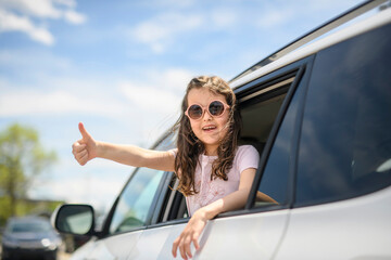 Wall Mural - Young girl looking out of car window smiling