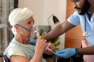 african american male health worker helping caucasian senior woman to use oxygen mask