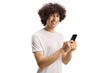 © Ljupco Smokovski - Casual young man with a curly hair using a smartphone and looking at camera