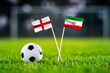 England vs. Iran, Khalifa Stadium, Football match wallpaper, Handmade national flags and soccer ball on green grass. Football stadium in background. Black edit space.