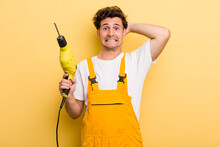Young Handsome Guy Feeling Stressed, Anxious Or Scared, With Hands On Head. Handyman With A Drill Concept