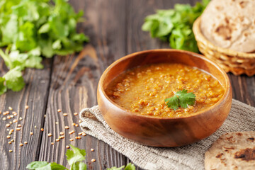 Indian dal food (Masoor Dal or Dal Tadka Curry) and homemade Flatbread Chapati. Traditional Indian soup lentils. Indian Dhal spicy curry in bowl, spices, herbs, rustic black wooden background.