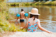 Children Have Fun And Play In The Water In A Pond Outside The City In The Village On Summer Holidays.