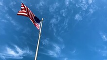 An American Flag Waving Against A Blue Sky 4K
