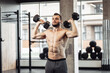 © splitov27 - Athletic man with a naked torso trains his shoulders with dumbbells in his hands. Workout in the gym. Bodybuilding and fitness, healthy lifestyle