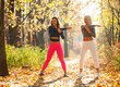 © splitov27 - Two fitness women practice arm stretching in autumn forest