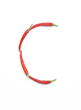 Letter C made from red chilli peppers isolated on white background