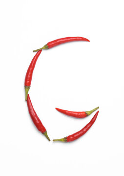 Letter G made from red chilli peppers isolated on white background