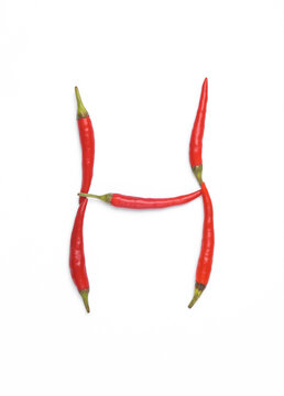 Letter H made from red chilli peppers isolated on white background