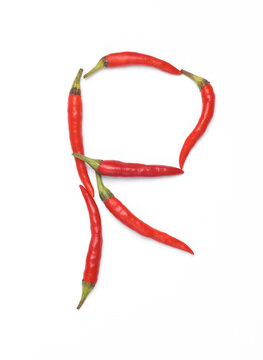 Letter R made from red chilli peppers isolated on white background