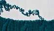 Dissolve hand knitted knitwear made of thick yarn with a braid pattern. edge of knitting with open loops and wavy thread on light background. untangling related things