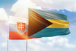 Sunny blue sky and flags of bahamas and slovakia