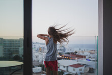 Girl With Long Hair Stay On The Balcony Watch And Dream. Summer Time Evening Sunset, Seaside.