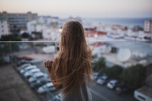 Girl With Long Hair Stay On The Balcony Watch And Dream. Summer Time Evening Sunset, Seaside.