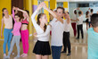 © JackF - Teenagers in pairs learning to dance active boogie-woogie with female choreographer in modern studio
