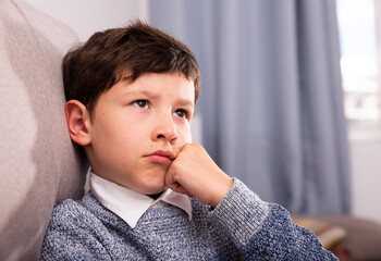 Wall Mural - Upset preteen boy sitting at sofa and thoughtful about problems at home