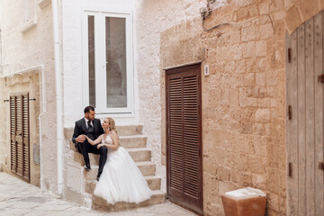 Two overdressed people, groom and bride, woman and man, just married. Hugging, sitting together, look each other, church