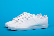 Pair Of New White Sneakers On Blue Background