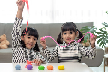 Wall Mural - The little girl is learning to use colorful play dough in a well lit room