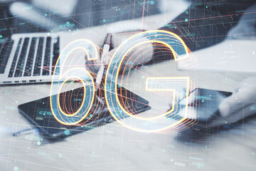 Poster - Close up of businessman hands using laptop, tablet and smartphone at desktop with abstract 6G hologram on blurry background. Internet, future and connectivity concept. Double exposure.