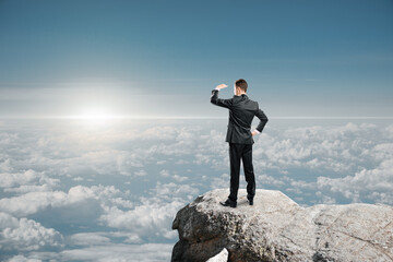 Poster - businessman standing on cliff and looking into the distance on bright blue sky and clouds background with mock up place for your advertisement. Market research, exploration and future concept.