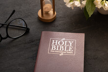 Top View Of The Holy Bible On The Desktop With Hourglass. The Concept Of Bible Study Time
