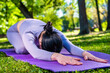 © frimufilms - Attractive girl with long black hair dressed in purple doing yoga pose - The Child Pose, in the green park
