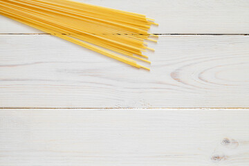 Wall Mural - Spaghetti, raw pasta, on white wooden board background, top view, space to copy text.