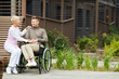 © Mediaphotos - Smiling mature mother sitting on bench and stroking son in wheelchair while she visiting him in recovery center